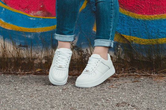 White sneakers on girl legs on the graffiti background