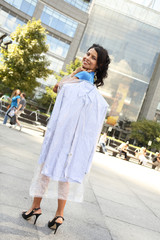 Full length shot of woman carrying a professionally cleaned and bagged shirt over her shoulder.