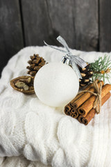 Knitted scarf, cinnamon, pine cones on a wooden background