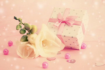 Fototapeta na wymiar Beautiful little gift box and freesia flower on pink background