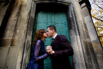 Wedding couple kissing on the background of wall and trees