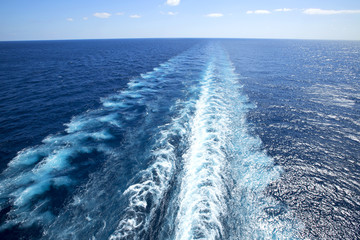 Trail on water surface behind of cruise ship.