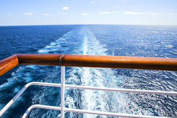 Trail on water surface behind of cruise ship.