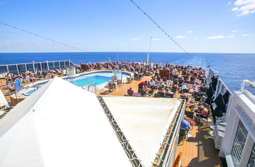 Tourists relax and take a sun bath on the upper deck of a cruise