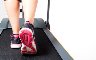 Girl doing cardio training on treadmill on pink black sport shoes whitespace on right