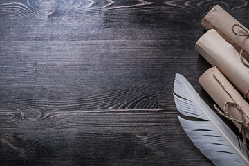 Ancient paper scrolls feather on wooden board copyspace