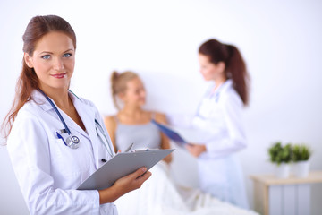 Fototapeta premium Smiling female doctor with a folder in uniform standing at hospital