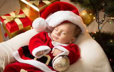 Fototapeta na wymiar newborn baby boy in Santa clothes lying under Christmas tree