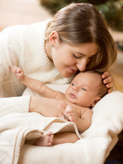 portrait of caring mother kissing baby boy son lying on white bl