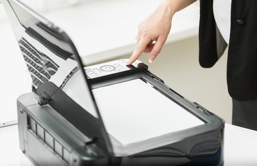 Closeup of businesswoman pressing knob on copying machine at off