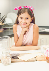 portrait of cute smiling girl posing on kitchen while making dou