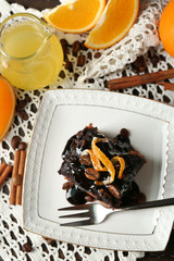 Portion of Cake with Chocolate Glaze and orange on plate, on wooden background