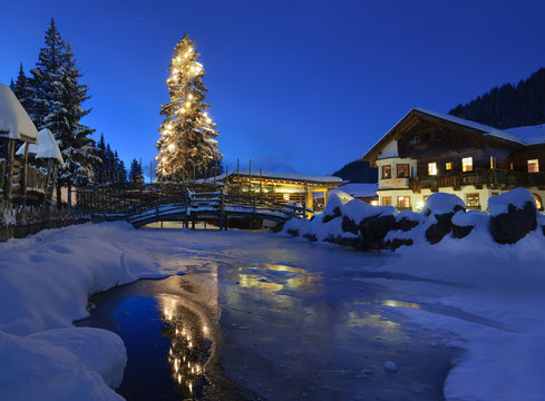 Illuminated christmas tree, lake and house under the snow