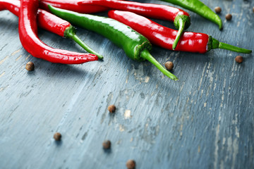 Hot peppers with spices on wooden table close up