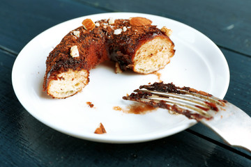 Piece of delicious doughnut with chocolate icing with fork on table close up