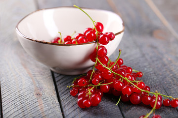 Fresh red currants in bowl on wooden table close up