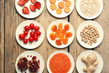 Different products on saucers on wooden table, top view
