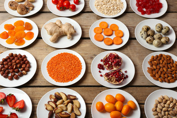 Different products on saucers on wooden table, top view