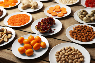 Different products on saucers on wooden table close up