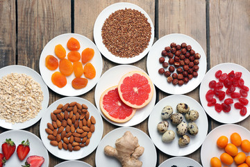 Different products on saucers on wooden table, top view