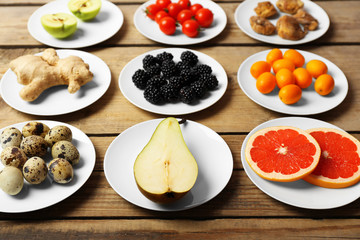 Different products on saucers on wooden table close up