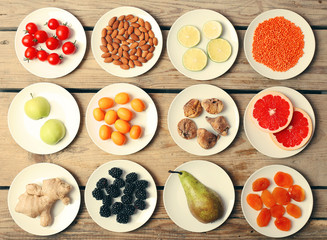 Different products on saucers on wooden table, top view