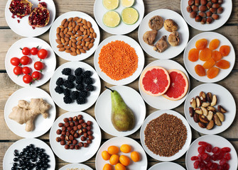 Different products on saucers on wooden table, top view