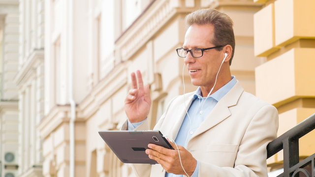 Businessman is using tablet out-of-doors.