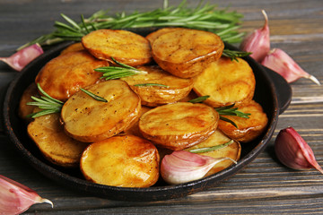 Delicious baked potato with rosemary in frying pan on table close up