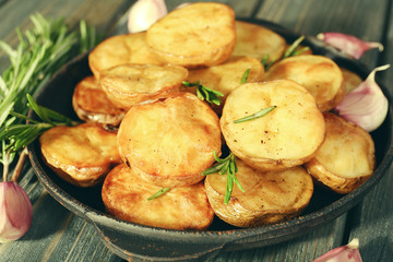 Delicious baked potato with rosemary in frying pan on table close up