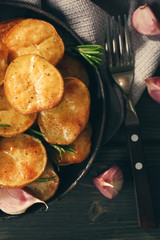 Delicious baked potato with rosemary in frying pan on table close up