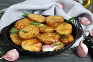 Delicious baked potato with rosemary in frying pan on table close up