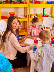 Children with teacher woman painting on paper in  kindergarten