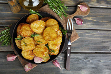 Delicious baked potato with rosemary in frying pan on table close up