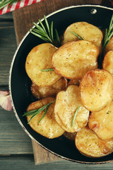 Delicious baked potato with rosemary in frying pan on table close up