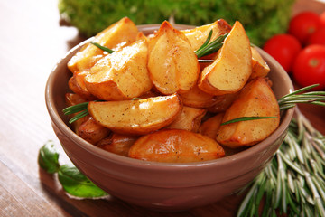 Baked potato wedges on wooden table, closeup