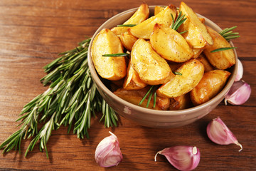 Baked potato wedges on wooden table, closeup