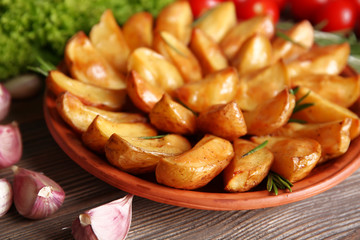 Baked potato wedges on wooden table, closeup