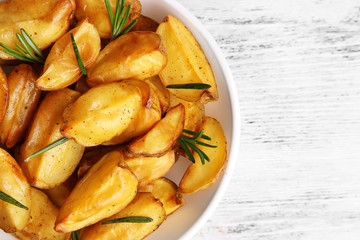 Baked potato wedges on wooden table, top view