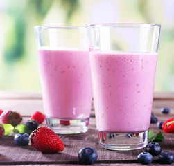 Glasses of berry smoothie on wooden table on blurred background