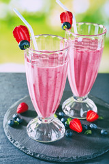 Glasses of berry smoothie on wooden table on blurred background