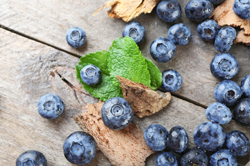 Tasty ripe blueberries with green leaves on wooden table close up