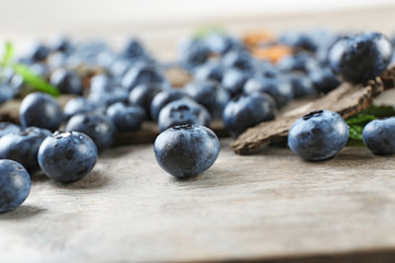 Tasty ripe blueberries with green leaves on wooden table close up