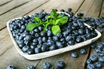 Tasty ripe blueberries with mint on wooden table close up