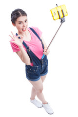 Young woman taking picture with smartphone selfie stick