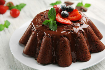 Delicious chocolate cake with berries in plate on table, closeup