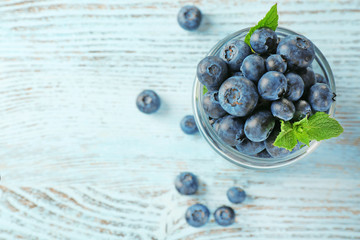 Fresh blueberries in jar on wooden table close up