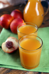 Peach juice and ripe peaches on wooden background