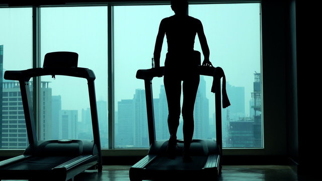 Young Woman Walking On Treadmill In Gym
