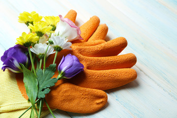 Beautiful composition of flower bouquet and garden gloves on light wooden background